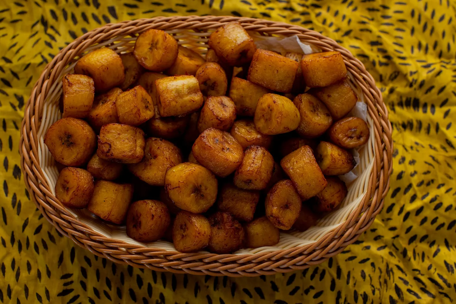 Panier d'alloco doré posé sur un pagne wax jaune
