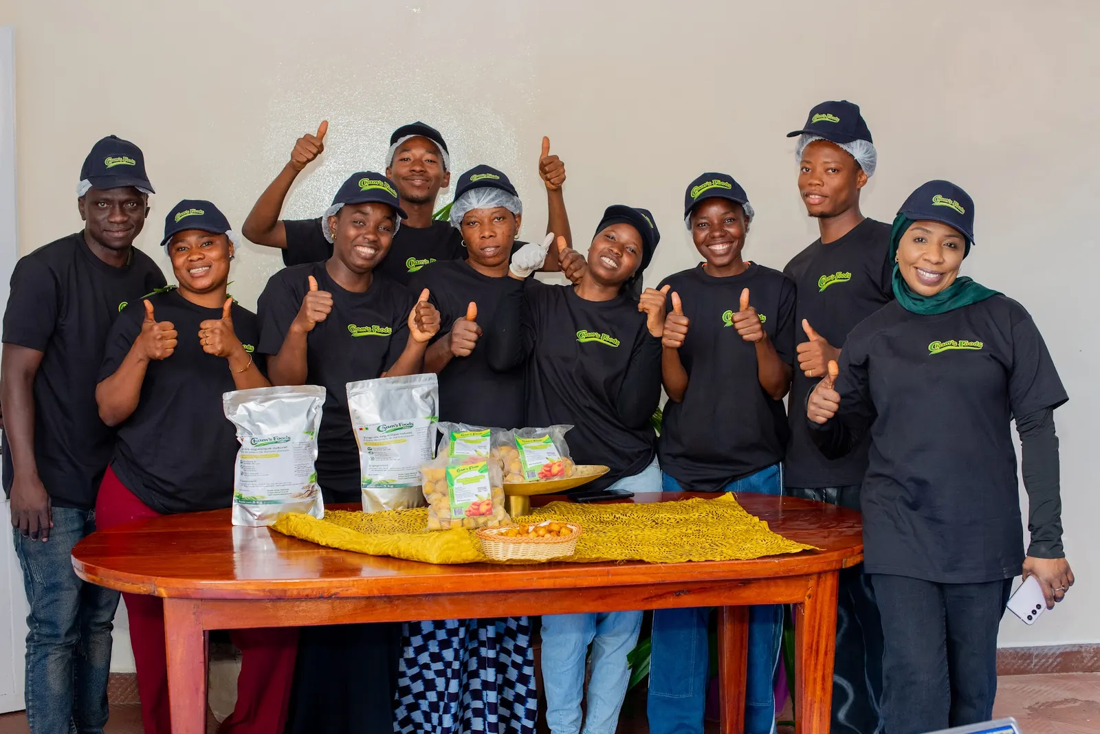 L'équipe Cham's Foods, pouces levés, derrière une table de produits